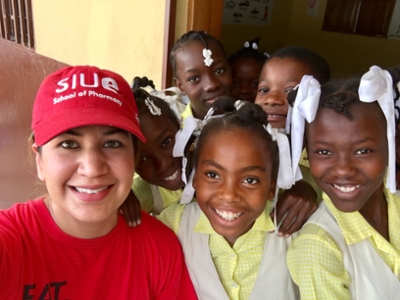 Misty Gonzalez, PharmD, clinical associate professor in the SIUE School of Pharmacy smiles with a group of girls from Haiti while participating in a medical mission trip.