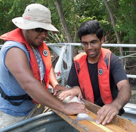 (L-R) Daniel Morales and Ayush Kumar measure a fish they captured via electrofishing. Once they gathered the necessary data, the fish was safely returned to the Mississippi.