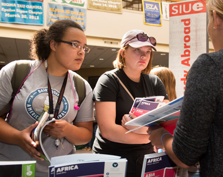 (L-R) Freshmen Ciara Marold and Hayleigh Lutz listen intently to a representative at the SIUE Study Abroad Fair.
