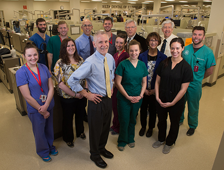 Third and fourth year SIU School of Dental Medicine students stand in their clinical uniforms among faculty members of the newly formed Department of Clinical Dentistry. Department Chair Steven Hoffman, DMD, (front) is joined by fellow team leaders (L-R) Morgan Emery, DDS, Jack Marincel, DDS, Vince Rapini, DDS, Katherine Weber, DMD, and Dean Drake, DMD.