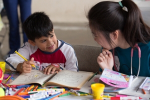 SON student Yu Cao colors with a young boy. 