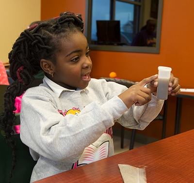Second grade student Zylah Howard looks excitedly at the soil sample her group collected for a lesson on soil chemistry.