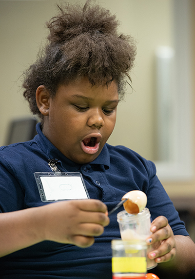 Nine-year-old Coriana Lampkins reacts to results of an experiment that demonstrated how different beverages can affect an egg shell, which represented teeth