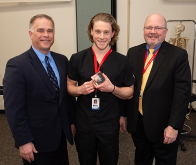 (L-R) Dentsply Sirona’s Joel Pluymert presented a first-place award for the Student Table Clinic Competition to second-year student Hunter Watson. Standing with them is SIU SDM Dean Bruce Rotter, DMD.