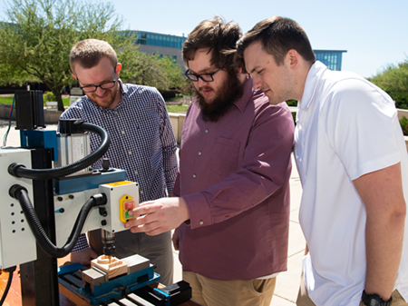SIUE senior Samuel Gass (middle) and his project team members demonstrate the mill they automated.