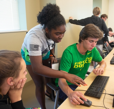 SIUE junior mechanical engineering student and camp counselor Daeja Daniels, of Peoria, (back) offers guidance to a camp participant during a robotics activity.