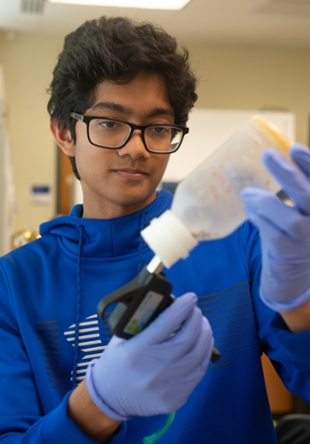 Summer Research Academy participant Sid Das, a junior at Parkway West High School in Chesterfield, Mo., injects CO2 into a fly culture bottle to anesthetize flies and transfer them to a new bottle.