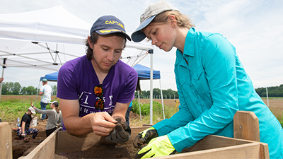 REU participant Roland Sanchez from Colorado (left) and Genevieve Zilmer from Chicago (right) look closely at an artifact found at the archeological site on SIUE’s campus.