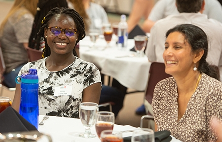 First-year pharmacy student Mimi Osei Larbi (left) and Radhika Devraj, PhD, associate professor in the Department of Pharmaceutical Sciences, smile while sharing conversation during the luncheon.