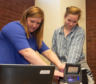 Heather Frank, with the Regional Office of Education, takes the finger prints of senior psychology major Sarah Love, who signed up to become a Give 30 mentor.
