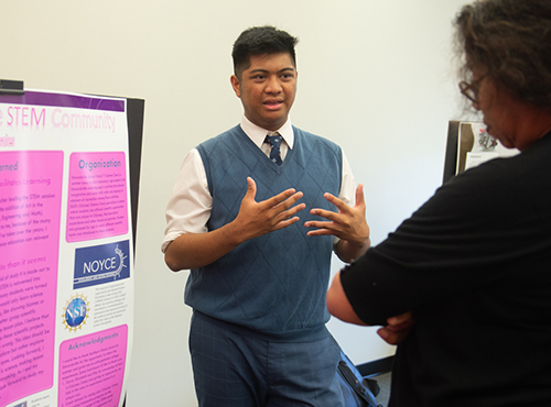 SIUE sophomore Justin Rosales recaps his summer experience to School of Education, Health and Human Behavior Dean Robin Hughes, PhD, at the Noyce Summer Scholars Showcase.