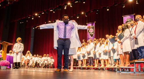 An SIU SDM student receives his white coat during the celebratory ceremony.