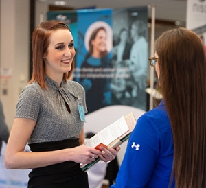 A student and prospective employee engage during a career fair on campus. 