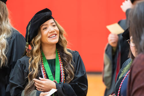 An SOP graduate smiles while gathering with peers ahead of the spring 2022 commencement ceremony.