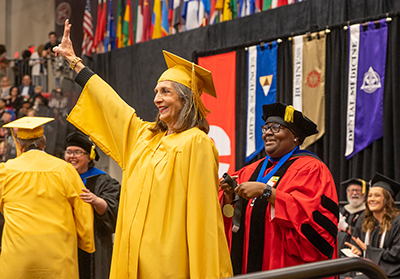 Sharon Stich ’72 smiles broadly and gives a peace sign while being honored during the SIUE commencement ceremony.