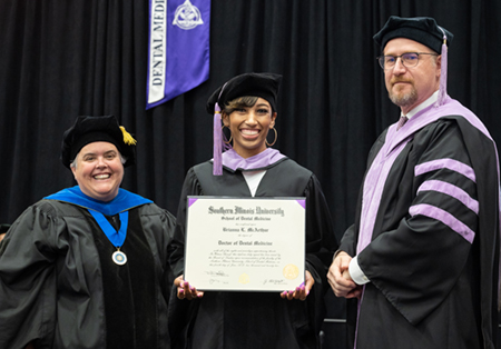 Brianna McArthur was among the graduates of the SIU SDM Class of 2022. She holds her diploma with SIUE Provost and Vice Chancellor for Academic Affairs Denise Cobb, PhD, (left) and SIU SDM Associate Dean for Academic Affairs Saulius Drukteinis, DMD (right).