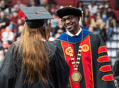 Chancellor James T. Minor, PhD, congratulates a graduate as they cross the commencement stage.