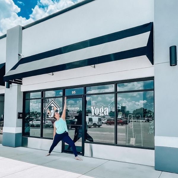Heather Garrigus in a yoga pose in front of her studio