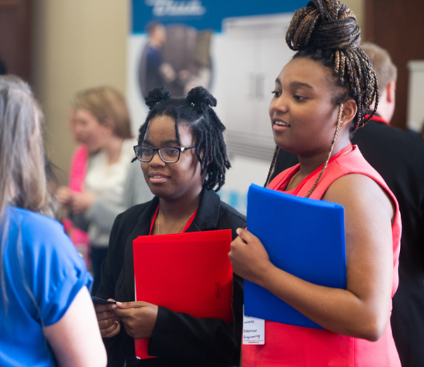 Two students speak to vendor at career fair from photo archive