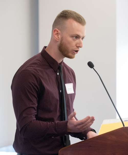 Hughes speaking into a microphone