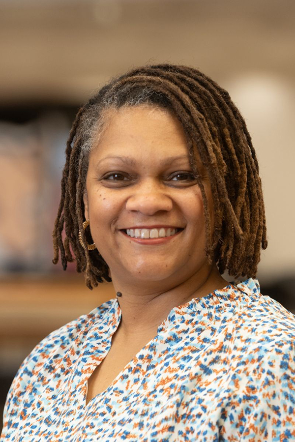 Portrait of Elizabeth Barnes smiling, and wearing a patterned blouse.