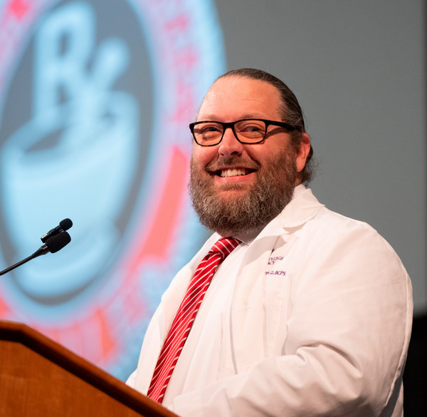Dr Golden Peters stands and smiles at podium