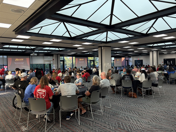 Wide shot of room with full tables of people playing trivia