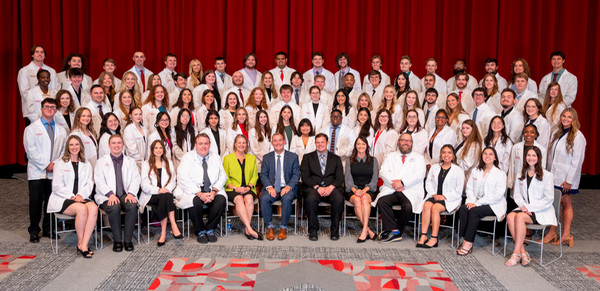 Group shot of SOP students wearing white coats with Dean Luer