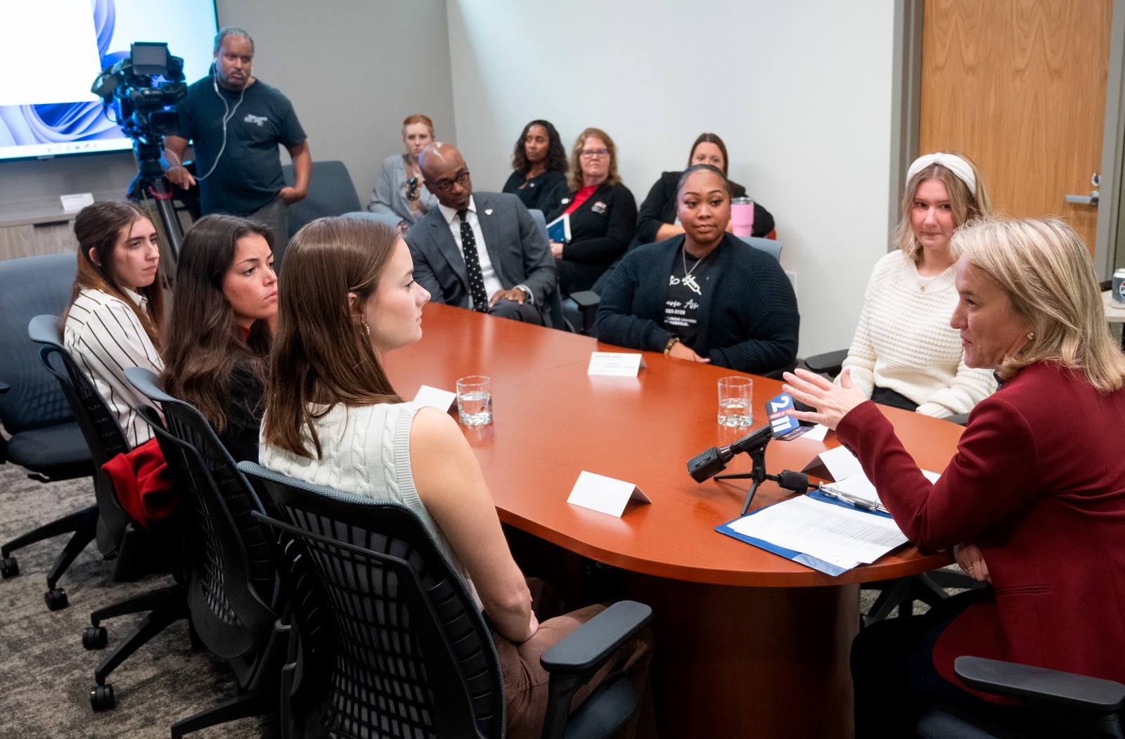 Congresswoman Nikki Budzinski sits at a roundtable surrounded by five nursing students, chancellor minor, and reporters