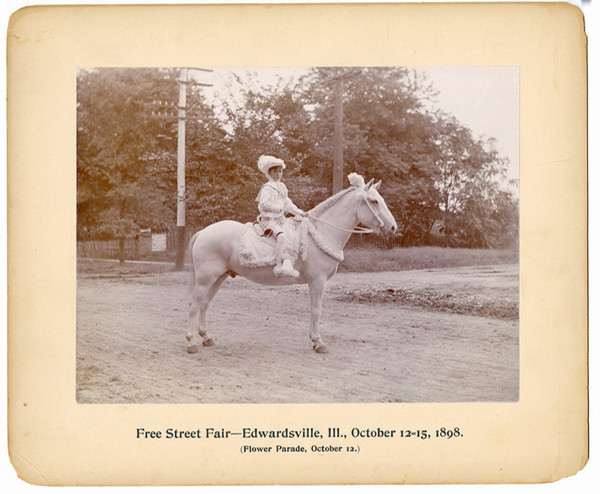 Black and white photo of boy on horse dressed in flowers for flower parade