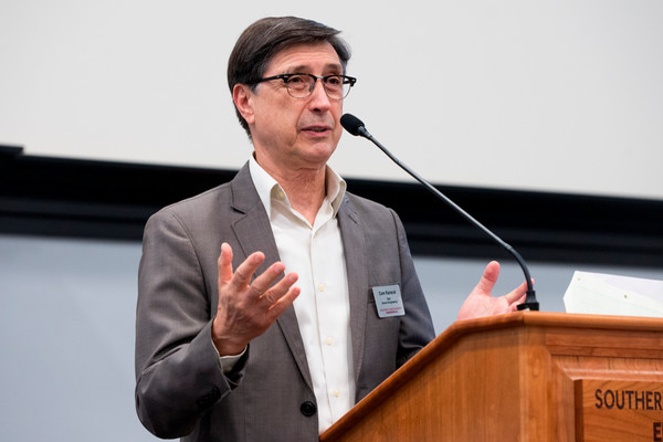 Dean Karacal speaks at a podium