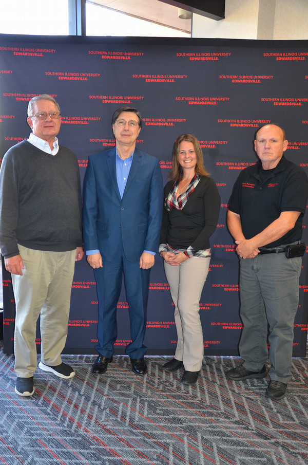 Four people who are keynote speaker and dept heads stand in front of background