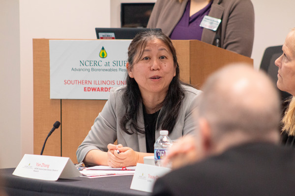 Dr Yan at table talking to board 