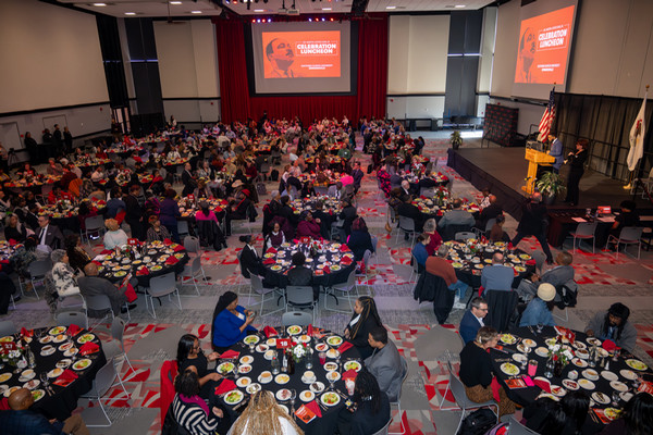 Birds eye view of guests at multiple tables in ballroom with MLK graphic projected on the screen