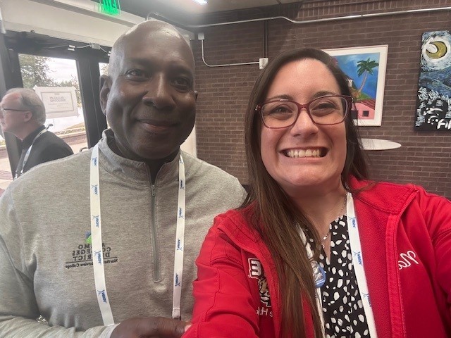 Natalie Rosales-Hawkins smiles for a selfie with her mentor, Tony Daniels, at the ERSL Conference, both wearing conference badges inside a meeting space.