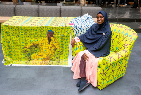 Student sits by table with her customized quilt display