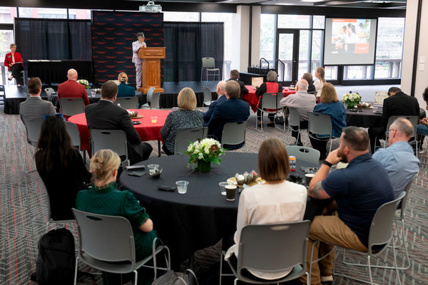 Audience at tables listening to speaker at podium
