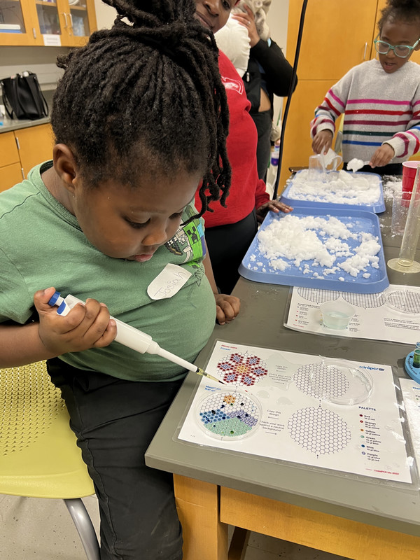 Little girl works on science project with lab tool at table