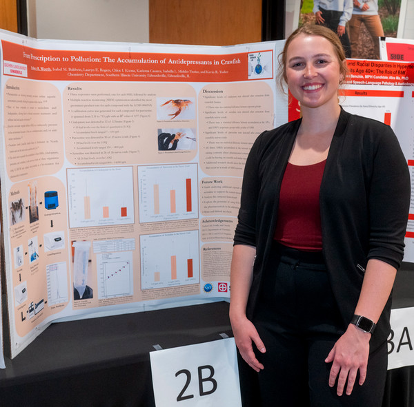 Student stands in front of poster presentation