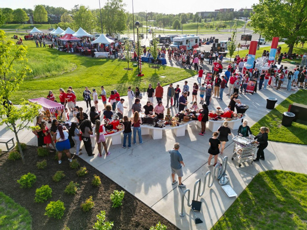 Aerial photography of the layout of One Day, One SIUE on a sunny afternoon looking towards the main campus. There are tents and people and food for sharing