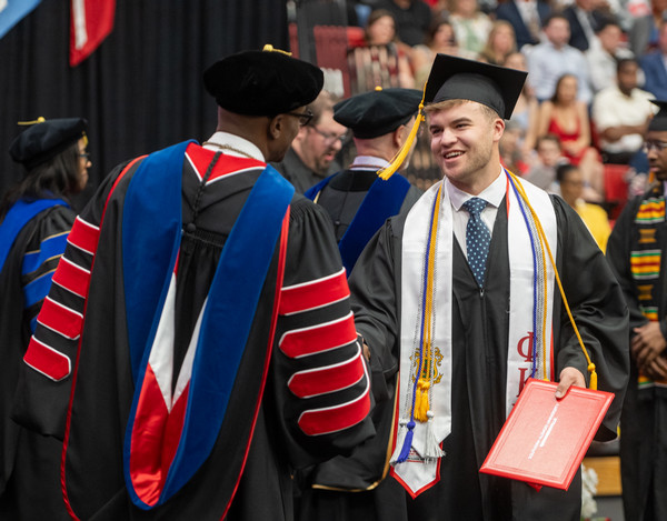 Student Alexander Robert Patrick shakes hands with Chancellor James T Minor as he crosses the commencement stage