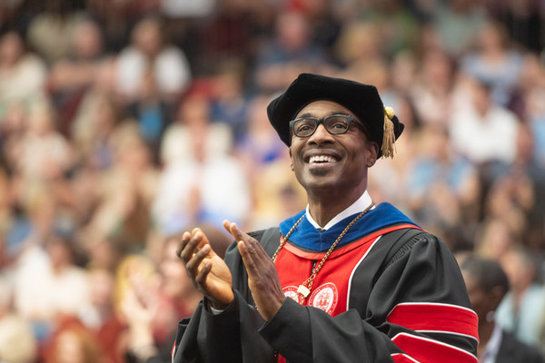 Chancellor Minor applauds graduates while looking up at crowds from the stage