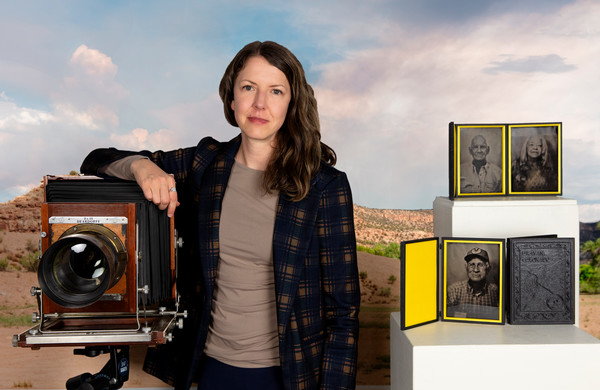 Portrait of Abbey Hepner with her arm resting on large camera