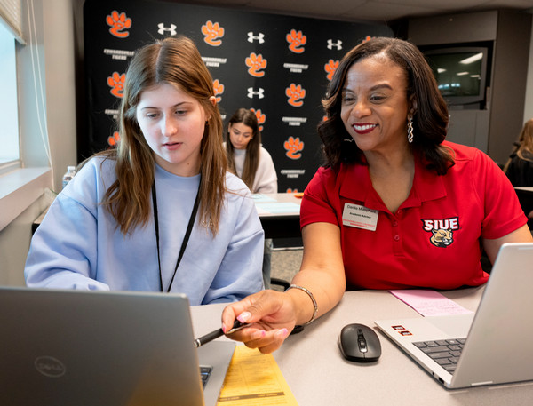 SIUE staff member showing SIUE material on computer to EHS student