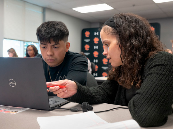 SIUE staff member pointing to SIUE material on laptop to EHS student
