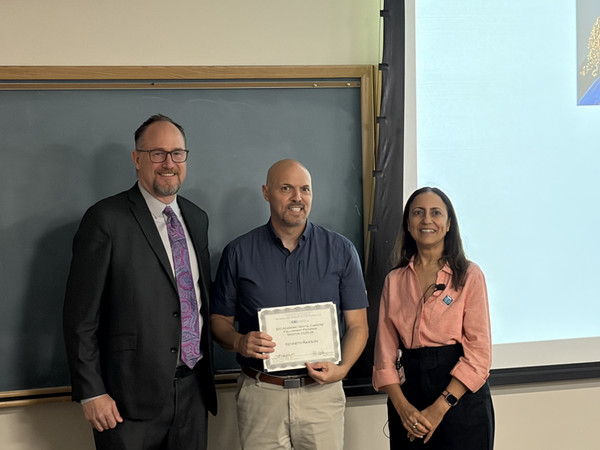 Dean of dental school stands with student graduate holding certificate and professor