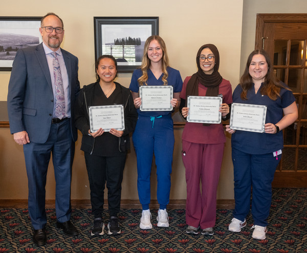SIU SDM Dean poses with student awardees who are holding plaques