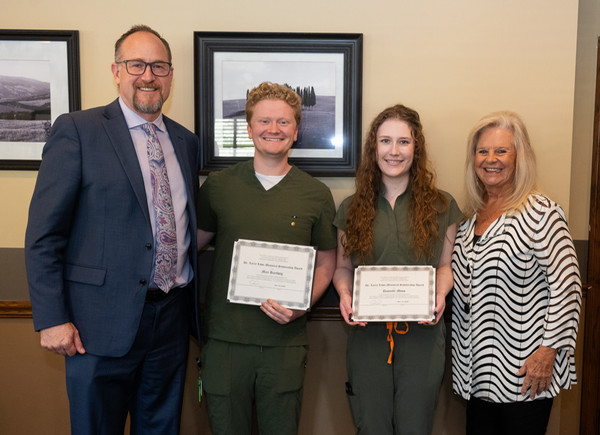 Two student awardees hold their framed awards