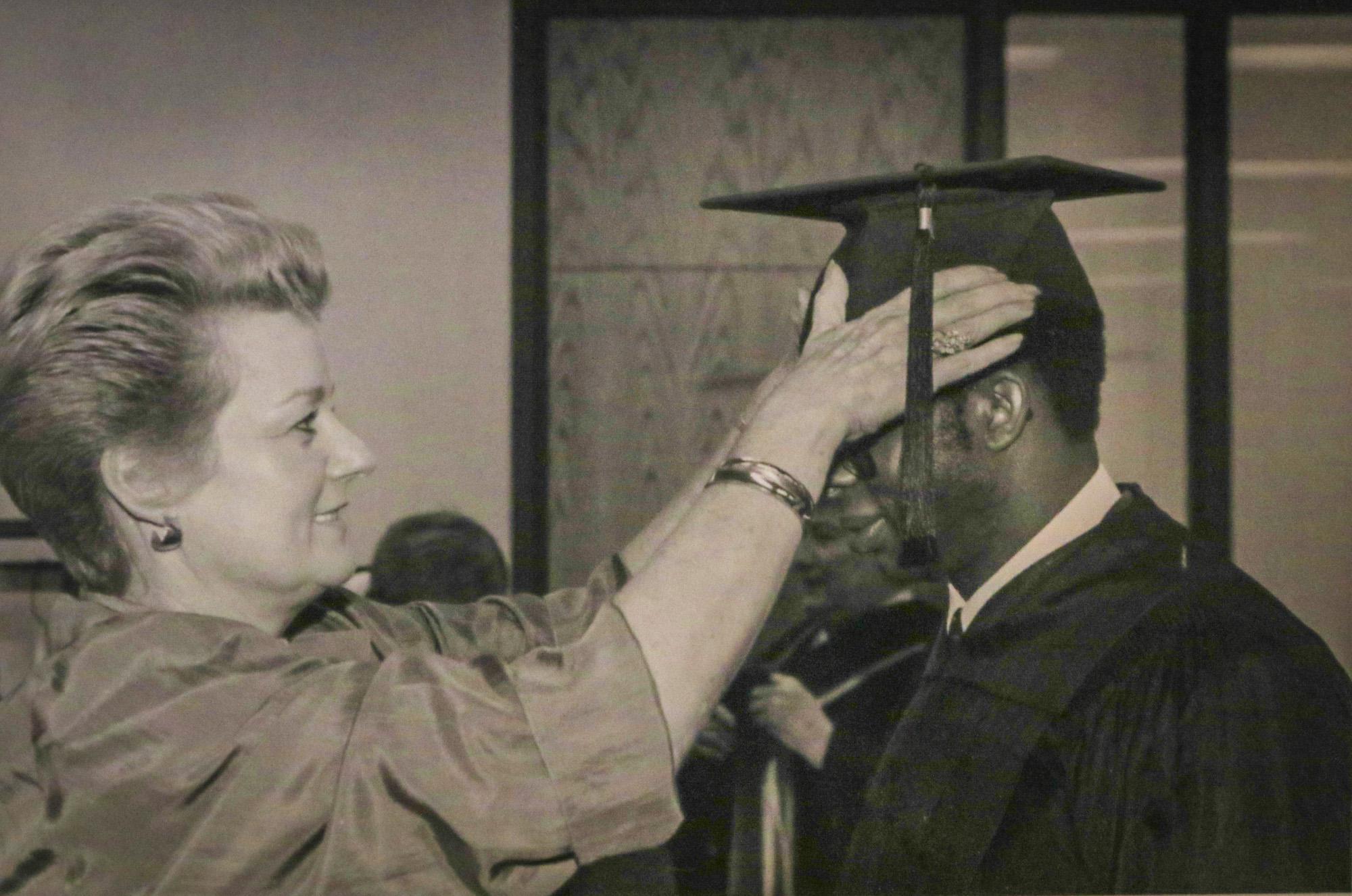 Bond adjusting the mortarboard of a graduating student, black and white archival photograph