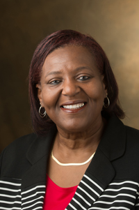 Professional portrait of Venessa Brown wearing a red blouse and black striped suit,